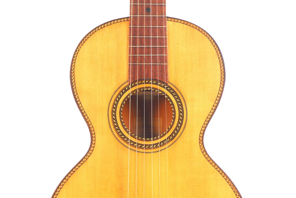 Nahaufnahme des Korpus und des Halses der Marc Antonio Romantikgitarre mit Holzoberfläche, Zierrosette um das Schallloch und detaillierten Einlegearbeiten vor weißem Hintergrund. Nahaufnahme des Korpus und des Halses der Marc Antonio Romantikgitarre mit Holzoberfläche, Zierrosette um das Schallloch und detaillierten Einlegearbeiten vor weißem Hintergrund.