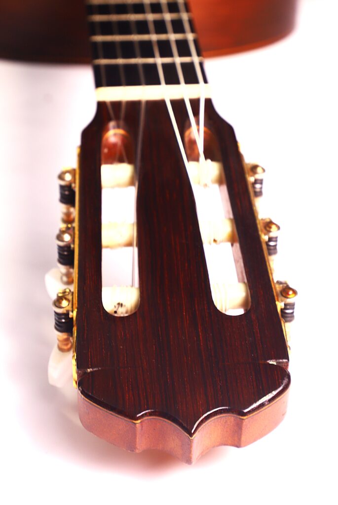 Nahaufnahme der Kopfplatte einer Jose Ramirez 1a 1959 PB Klassische Gitarre mit Holzoberfläche, Stimmwirbeln und Nylonsaiten vor weißem Hintergrund. Nahaufnahme der Kopfplatte einer Jose Ramirez 1a 1959 PB Klassische Gitarre mit Holzoberfläche, Stimmwirbeln und Nylonsaiten vor weißem Hintergrund.