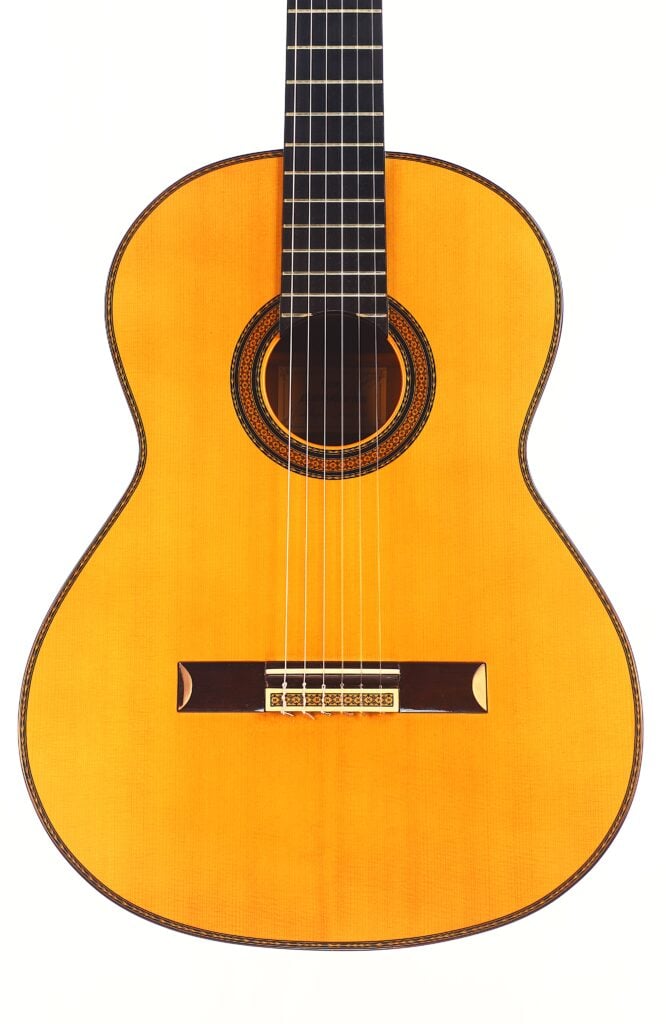 Die Manuel Contreras Double Top 1985 Klassische Gitarre hat ein helles Holzfinish, ein dunkles Griffbrett, sechs Saiten und eine dekorative Rosette um das Schallloch, die auf weißem Hintergrund zu sehen ist. Die Manuel Contreras Double Top 1985 Klassische Gitarre hat ein helles Holzfinish, ein dunkles Griffbrett, sechs Saiten und eine dekorative Rosette um das Schallloch, die auf weißem Hintergrund zu sehen ist.