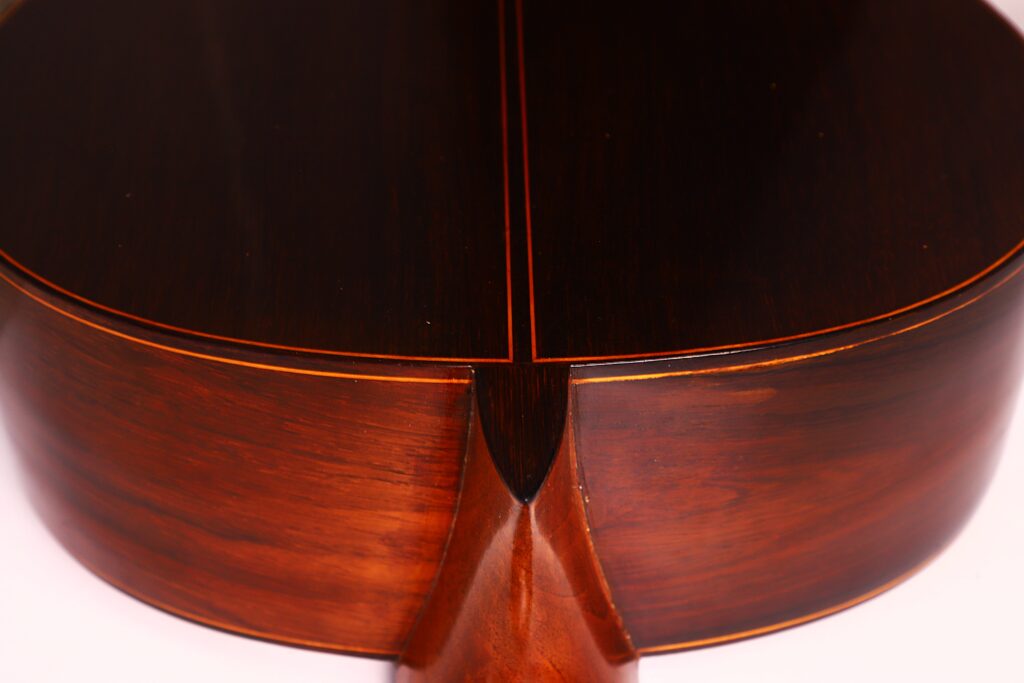 Nahaufnahme des Bodens und der Zargen einer Jose Ramirez 1a 1959 PB Klassische Gitarre, die die reiche, polierte Holzmaserung und die zentrale Naht hervorhebt. Nahaufnahme des Bodens und der Zargen einer Jose Ramirez 1a 1959 PB Klassische Gitarre, die die reiche, polierte Holzmaserung und die zentrale Naht hervorhebt.