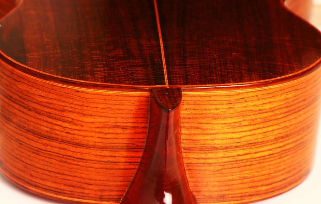 Nahaufnahme des Bodens und der Seite einer Faustino Conde Negra Flamenco-Gitarre von Hermanos Conde 1971. Hervorzuheben sind die glänzende, rötlich-braune Oberfläche und die fein ausgearbeitete Holzmaserung. Nahaufnahme des Bodens und der Seite einer Faustino Conde Negra Flamenco-Gitarre von Hermanos Conde 1971. Hervorzuheben sind die glänzende, rötlich-braune Oberfläche und die fein ausgearbeitete Holzmaserung.