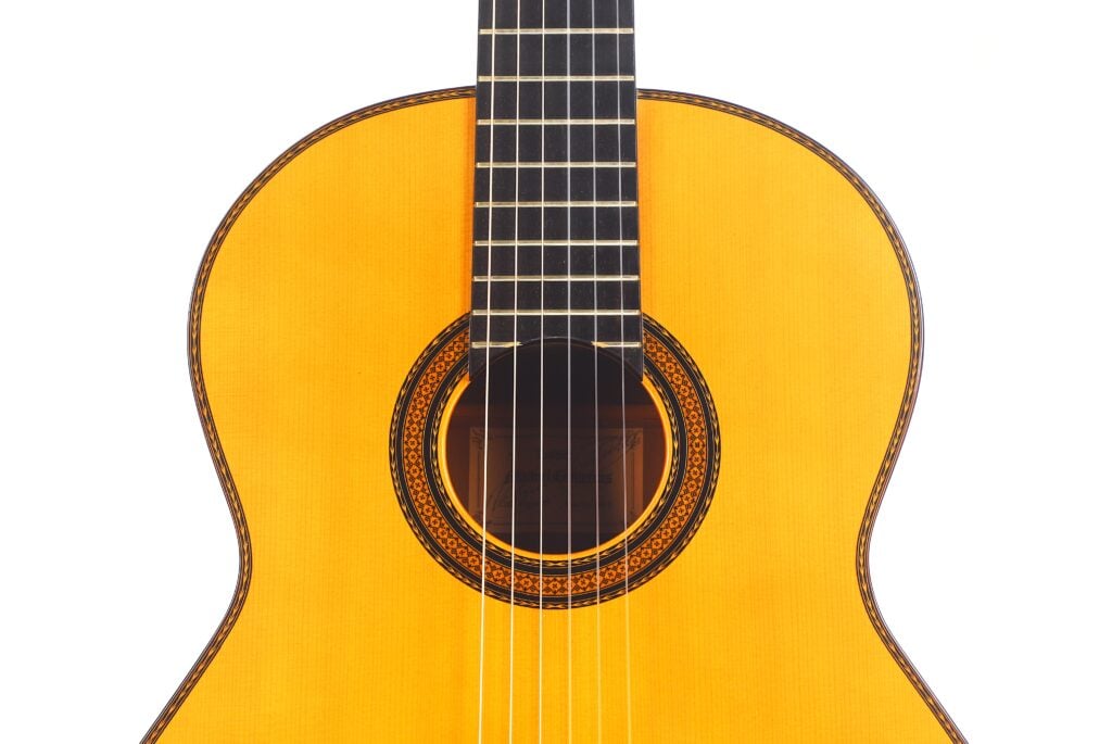 Nahaufnahme von Korpus und Hals der Manuel Contreras Double Top 1985 Klassische Gitarre mit Schallloch, Saiten und detailliertem Rosettenmuster auf weißem Hintergrund. Nahaufnahme von Korpus und Hals der Manuel Contreras Double Top 1985 Klassische Gitarre mit Schallloch, Saiten und detailliertem Rosettenmuster auf weißem Hintergrund.