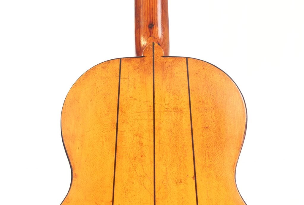 Nahaufnahme der Rückseite der Juan Lopez Jimenez 1933 Klassische Gitarre. Man sieht das natürliche Holzfinish mit zwei parallelen dunklen Linien auf dem Korpus und den Gitarrenhals, der an der Decke sichtbar ist. Nahaufnahme der Rückseite der Juan Lopez Jimenez 1933 Klassische Gitarre. Man sieht das natürliche Holzfinish mit zwei parallelen dunklen Linien auf dem Korpus und den Gitarrenhals, der an der Decke sichtbar ist.