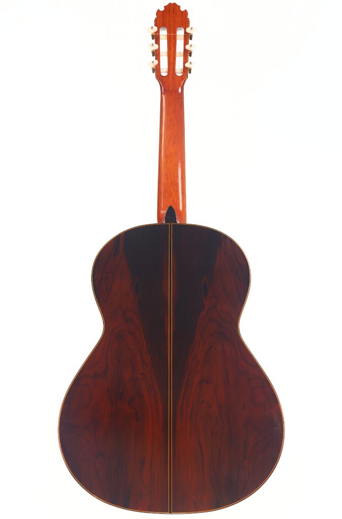 Das Bild zeigt die Rückansicht der Manuel Contreras Double Top 1985 Klassische Gitarre. Hervorzuheben sind das dunkle polierte Holz, die symmetrische Maserung und die goldenen Stimmwirbel an der Kopfplatte. Das Bild zeigt die Rückansicht der Manuel Contreras Double Top 1985 Klassische Gitarre. Hervorzuheben sind das dunkle polierte Holz, die symmetrische Maserung und die goldenen Stimmwirbel an der Kopfplatte.
