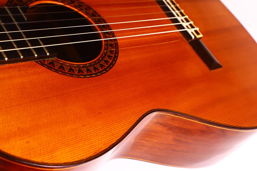 Nahaufnahme einer Jose Ramirez 1a 1959 PB Klassische Gitarre. Hervorzuheben sind das Schallloch mit dekorativer Rosette, Nylonsaiten und ein polierter, warm-brauner Holzkorpus. Nahaufnahme einer Jose Ramirez 1a 1959 PB Klassische Gitarre. Hervorzuheben sind das Schallloch mit dekorativer Rosette, Nylonsaiten und ein polierter, warm-brauner Holzkorpus.