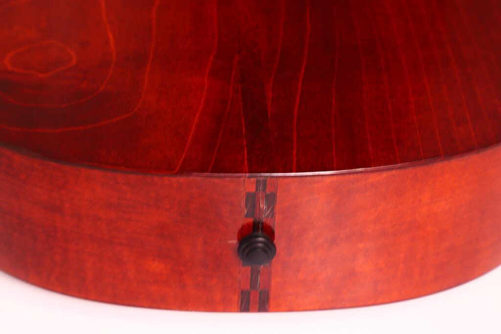 Nahaufnahme der Rückseite und der Seite der Marc Antonio Romantikgitarre. Hervorzuheben sind die glänzende rotbraune Holzoberfläche und der schwarze Bandknopf am unteren Rand. Nahaufnahme der Rückseite und der Seite der Marc Antonio Romantikgitarre. Hervorzuheben sind die glänzende rotbraune Holzoberfläche und der schwarze Bandknopf am unteren Rand.