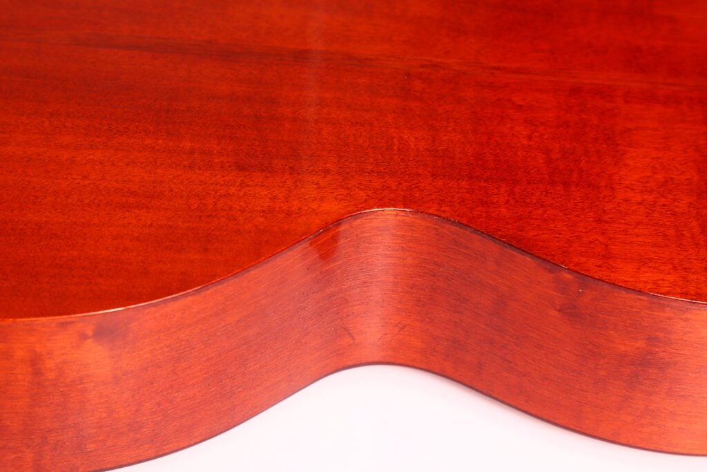 Nahaufnahme der Seite und der Rückseite der Marc Antonio Romantikgitarre. Hervorzuheben sind die glatte, rötlich-braune Oberfläche und die eleganten Kurven vor weißem Hintergrund. Nahaufnahme der Seite und der Rückseite der Marc Antonio Romantikgitarre. Hervorzuheben sind die glatte, rötlich-braune Oberfläche und die eleganten Kurven vor weißem Hintergrund.