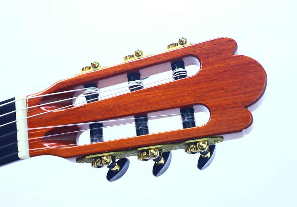 Nahaufnahme der Kopfplatte der Jellinghaus Torres 77 PU Klassische Gitarre, die die Wirbel, die Saiten und die elegante Holzoberfläche vor einem schlichten weißen Hintergrund hervorhebt. Nahaufnahme der Kopfplatte der Jellinghaus Torres 77 PU Klassische Gitarre, die die Wirbel, die Saiten und die elegante Holzoberfläche vor einem schlichten weißen Hintergrund hervorhebt.