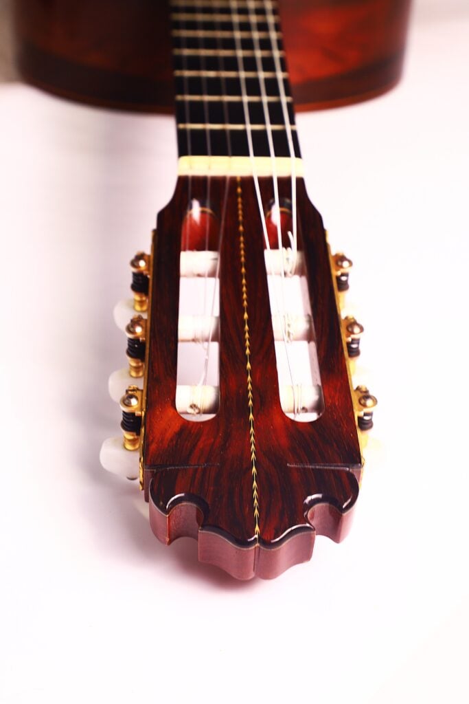 Nahaufnahme der Kopfplatte und der Stimmwirbel einer Manuel Contreras Double Top 1985 Klassische Gitarre. Hervorzuheben sind die Holzoberfläche, die weißen Knöpfe und die Nylonsaiten vor einem weißen Hintergrund. Nahaufnahme der Kopfplatte und der Stimmwirbel einer Manuel Contreras Double Top 1985 Klassische Gitarre. Hervorzuheben sind die Holzoberfläche, die weißen Knöpfe und die Nylonsaiten vor einem weißen Hintergrund.