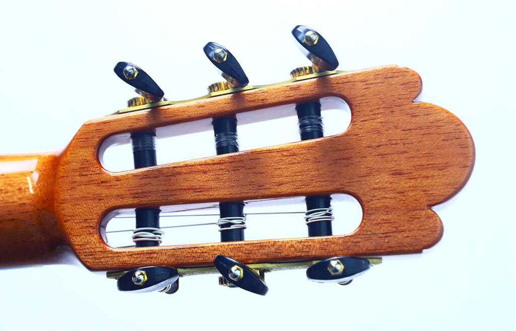 Nahaufnahme der Kopfplatte der Jellinghaus Torres 77 PU Klassische Gitarre mit sechs Stimmwirbeln, um die Nylonsaiten gewickelt sind, vor einem weißen Hintergrund. Nahaufnahme der Kopfplatte der Jellinghaus Torres 77 PU Klassische Gitarre mit sechs Stimmwirbeln, um die Nylonsaiten gewickelt sind, vor einem weißen Hintergrund.
