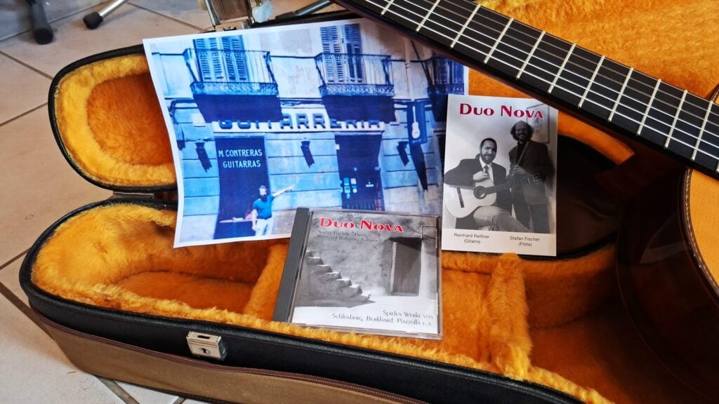Ein offener Gitarrenkoffer mit einer Manuel Contreras Double Top 1985 Klassische Gitarre, zwei Duo Nova CDs, ein Schwarz-Weiß-Foto von zwei Musikern und ein Farbfoto mit der Aufschrift "Guitarreria". Ein offener Gitarrenkoffer mit einer Manuel Contreras Double Top 1985 Klassische Gitarre, zwei Duo Nova CDs, ein Schwarz-Weiß-Foto von zwei Musikern und ein Farbfoto mit der Aufschrift "Guitarreria".