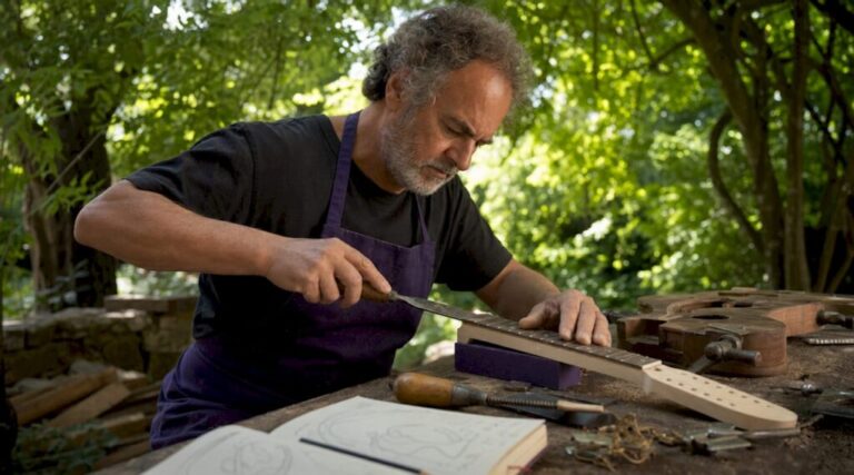 Luthier shaping vintage guitar neck in workshop