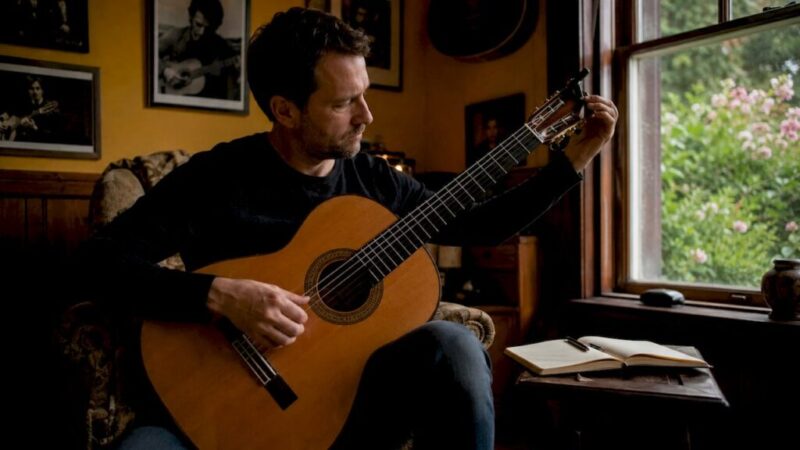 Im heimischen Arbeitszimmer bringt ein Gitarrist seine klassische Gitarre auf den richtigen Ton.