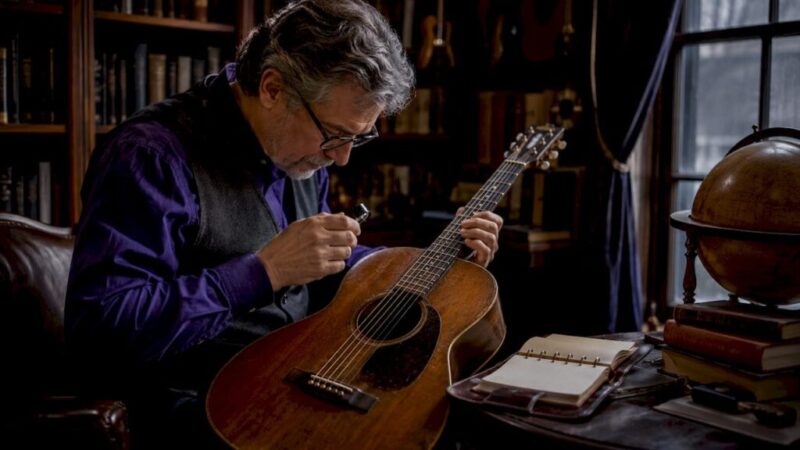 Collector examining vintage guitar in study