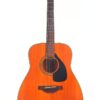 Eine Yamaha FG-180 50th Anniversary Akustik-Gitarre mit Naturholz-Finish, dunklem Schlagbrett und sechs Saiten wird in voller Ansicht vor einem schlichten weißen Hintergrund gezeigt. Eine Yamaha FG-180 50th Anniversary Akustik-Gitarre mit Naturholz-Finish, dunklem Schlagbrett und sechs Saiten wird in voller Ansicht vor einem schlichten weißen Hintergrund gezeigt.