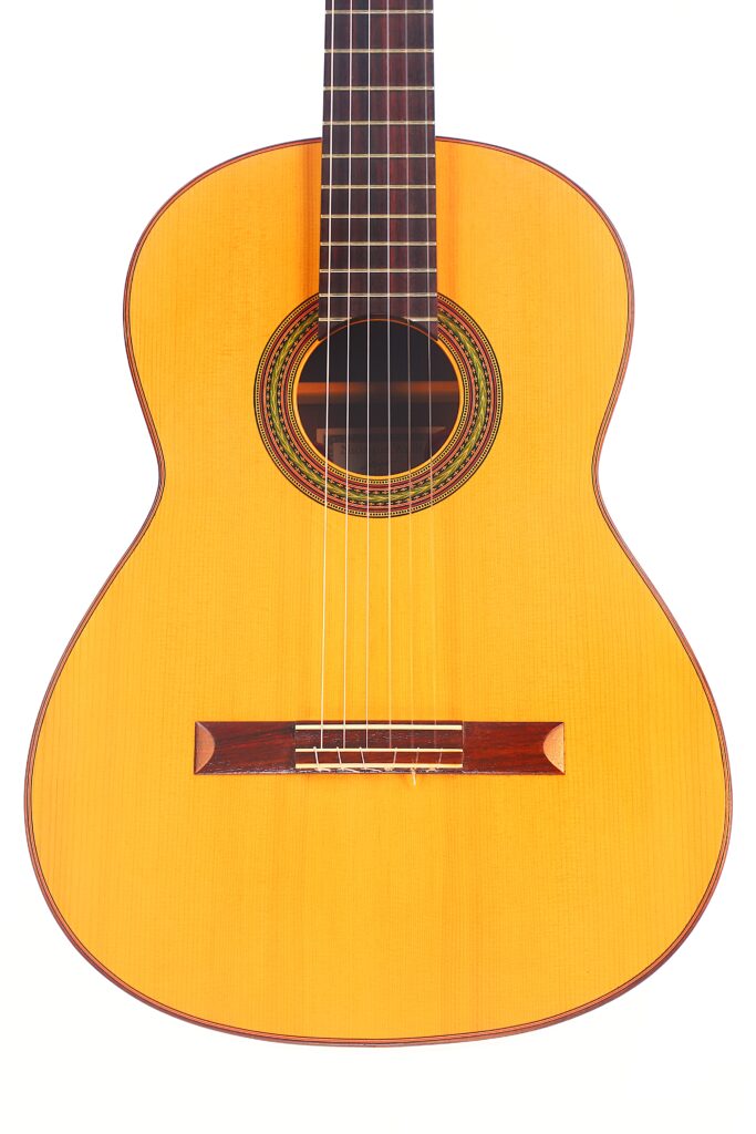 Die „Carl Hermann Schäfer – Nicolaus Wollf 2012“ Klassische Gitarre verfügt über einen hellen Korpus, einen dunklen Steg und eine Zierrosette um das Schallloch, abgebildet vor weißem Hintergrund. Die „Carl Hermann Schäfer – Nicolaus Wollf 2012“ Klassische Gitarre verfügt über einen hellen Korpus, einen dunklen Steg und eine Zierrosette um das Schallloch, abgebildet vor weißem Hintergrund.
