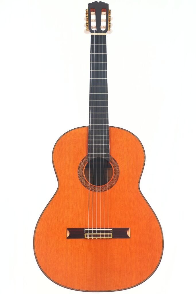 Die Juan Miguel Gonzalez 2006 Klassische Gitarre ist eine klassische Akustikgitarre mit einem Holzkorpus, einem dunklen Griffbrett und einer kunstvollen Rosette um das Schallloch, die vor einem weißen Hintergrund abgebildet ist. Die Juan Miguel Gonzalez 2006 Klassische Gitarre ist eine klassische Akustikgitarre mit einem Holzkorpus, einem dunklen Griffbrett und einer kunstvollen Rosette um das Schallloch, die vor einem weißen Hintergrund abgebildet ist.