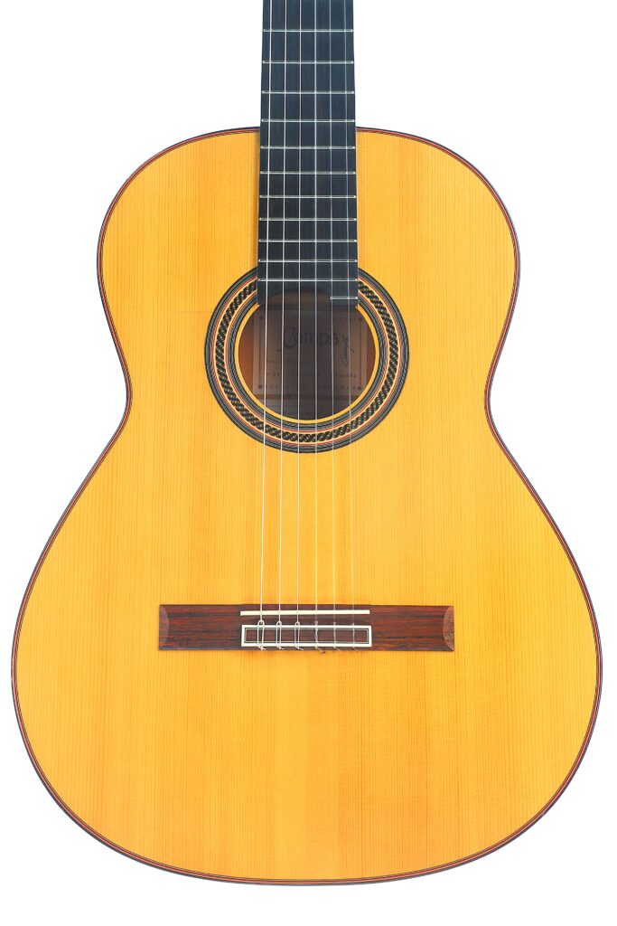 Die „Camps Primera A 2018“ Flamenco-Gitarre verfügt über einen Korpus aus hellem Holz, einen Steg aus dunklem Holz und ein rundes Schallloch; sie wurde vor einem weißen Hintergrund fotografiert. Die „Camps Primera A 2018“ Flamenco-Gitarre verfügt über einen Korpus aus hellem Holz, einen Steg aus dunklem Holz und ein rundes Schallloch; sie wurde vor einem weißen Hintergrund fotografiert.