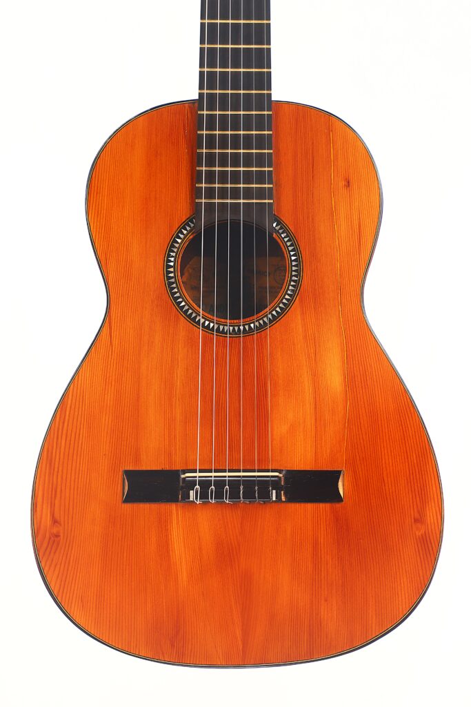Die Andres Marin 1890 Klassische Gitarre ist eine klassische Akustikgitarre mit einer natürlichen Holzoberfläche mit sichtbarer Maserung, einem runden Schallloch mit dekorativer Rosette, sechs Saiten und einem schwarzen Steg, abgebildet vor einem weißen Hintergrund. Die Andres Marin 1890 Klassische Gitarre ist eine klassische Akustikgitarre mit einer natürlichen Holzoberfläche mit sichtbarer Maserung, einem runden Schallloch mit dekorativer Rosette, sechs Saiten und einem schwarzen Steg, abgebildet vor einem weißen Hintergrund.