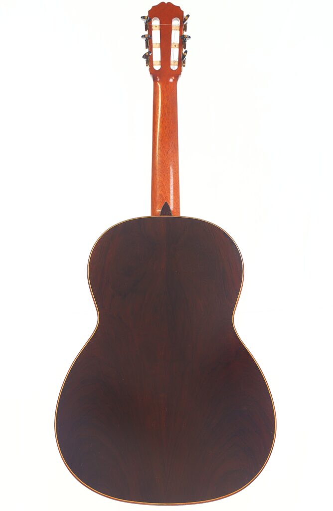 Die „Carl Hermann Schäfer – Nicolaus Wollf 2012 Klassische Gitarre“ ist hier von hinten zu sehen, wobei ihre satte, dunkle Holzmaserung und die glatte Oberfläche besonders gut zur Geltung kommen. Oben sind der Hals und die Stimmwirbel zu sehen. Die „Carl Hermann Schäfer – Nicolaus Wollf 2012 Klassische Gitarre“ ist hier von hinten zu sehen, wobei ihre satte, dunkle Holzmaserung und die glatte Oberfläche besonders gut zur Geltung kommen. Oben sind der Hals und die Stimmwirbel zu sehen.