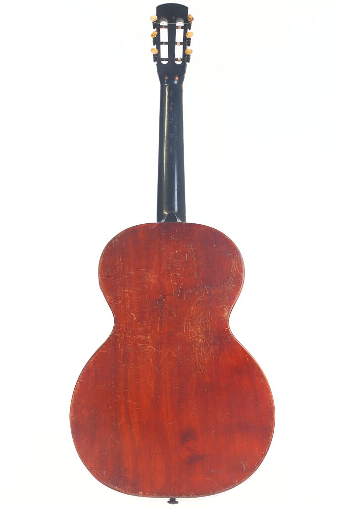 Das Bild zeigt die Rückansicht einer Braun & Hauser 1905 Klassische Gitarre mit dunklem Holzhals und rotbraunem, abgenutztem Korpus mit sichtbaren Kratzern und Schrammen, die auf Gebrauchsspuren hinweisen. Das Bild zeigt die Rückansicht einer Braun & Hauser 1905 Klassische Gitarre mit dunklem Holzhals und rotbraunem, abgenutztem Korpus mit sichtbaren Kratzern und Schrammen, die auf Gebrauchsspuren hinweisen.