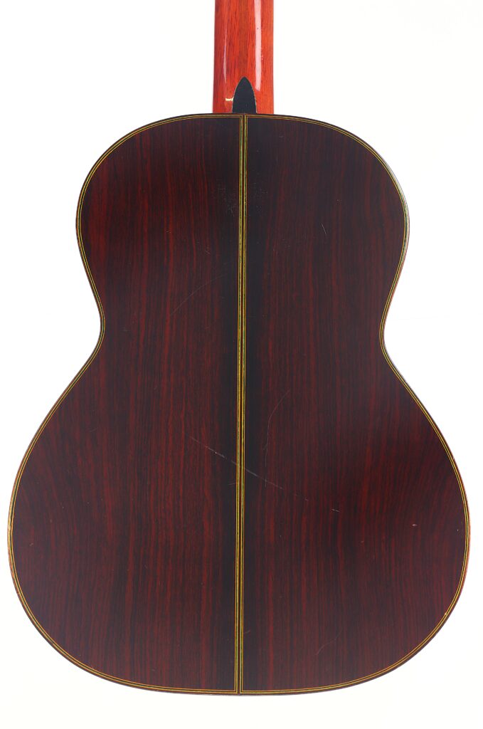Die Rückseite der „Juan Estruch Chet Atkins Yellow Label 1976 Klassische Gitarre“ weist eine glänzende, dunkle Holzoberfläche, eine dezente Holzmaserung und eine schmale Zierlinie auf, die vertikal in der Mitte verläuft. Die Rückseite der „Juan Estruch Chet Atkins Yellow Label 1976 Klassische Gitarre“ weist eine glänzende, dunkle Holzoberfläche, eine dezente Holzmaserung und eine schmale Zierlinie auf, die vertikal in der Mitte verläuft.