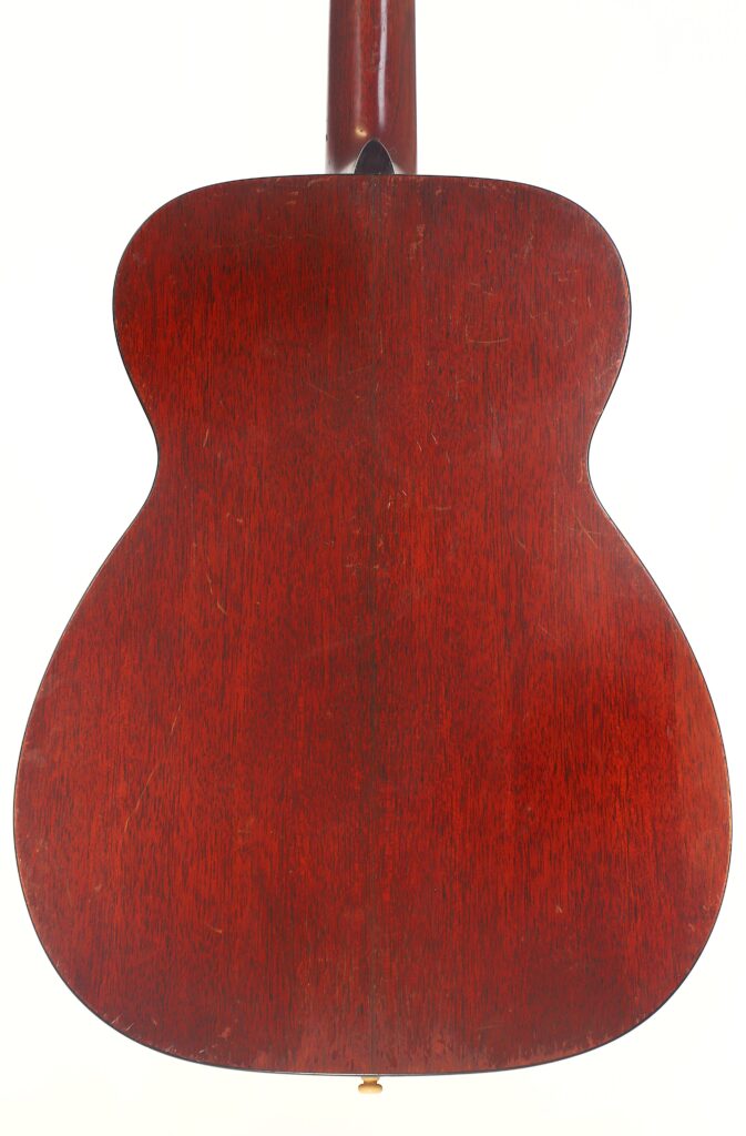Das Bild zeigt die Rückseite einer Martin 00-18 Akustikgitarre aus dem Jahr 1954 mit einer satten, dunkelrotbraunen Holzoberfläche, sichtbarer Maserung, leichten Kratzern auf der glatten Oberfläche und einem Teil des Halses im oberen Bereich. Das Bild zeigt die Rückseite einer Martin 00-18 Akustikgitarre aus dem Jahr 1954 mit einer satten, dunkelrotbraunen Holzoberfläche, sichtbarer Maserung, leichten Kratzern auf der glatten Oberfläche und einem Teil des Halses im oberen Bereich.