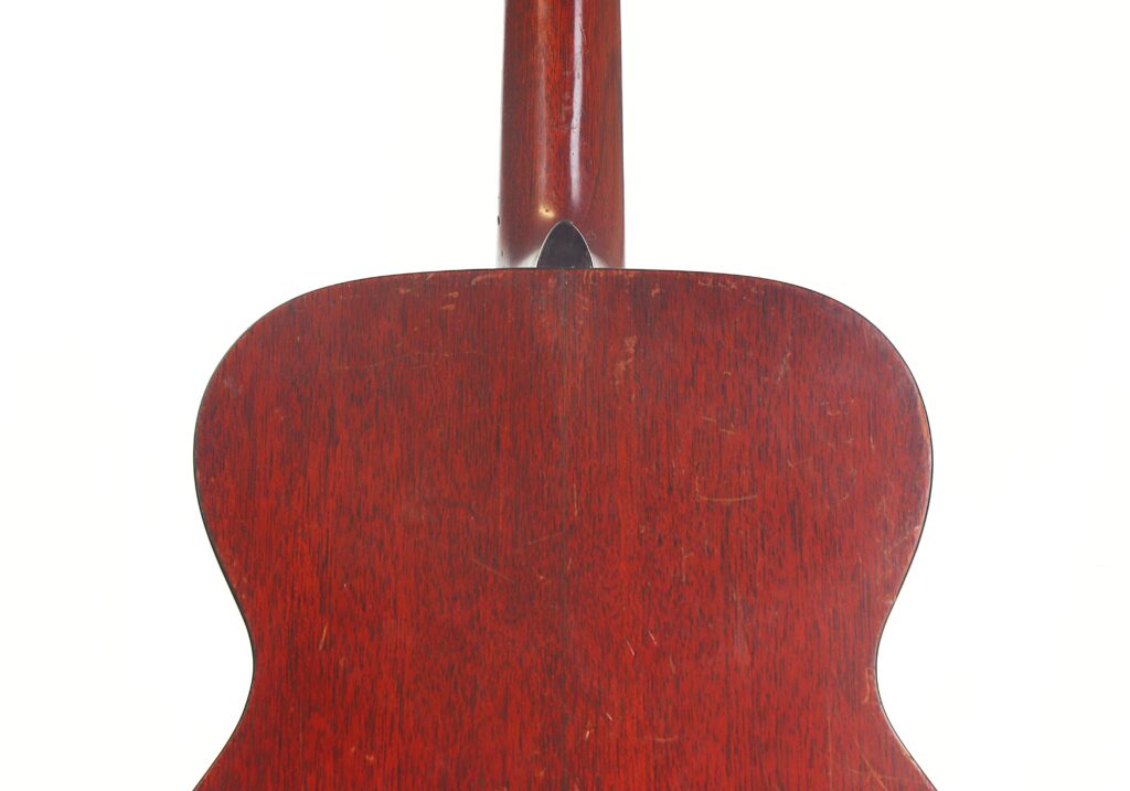 Nahaufnahme der Rückseite einer Martin 00-18 Akustikgitarre aus dem Jahr 1954, die das dunkelrotbraune Holzfinish und die sichtbare Maserung hervorhebt. Oben ist ein Teil des Gitarrenhalses zu sehen. Nahaufnahme der Rückseite einer Martin 00-18 Akustikgitarre aus dem Jahr 1954, die das dunkelrotbraune Holzfinish und die sichtbare Maserung hervorhebt. Oben ist ein Teil des Gitarrenhalses zu sehen.