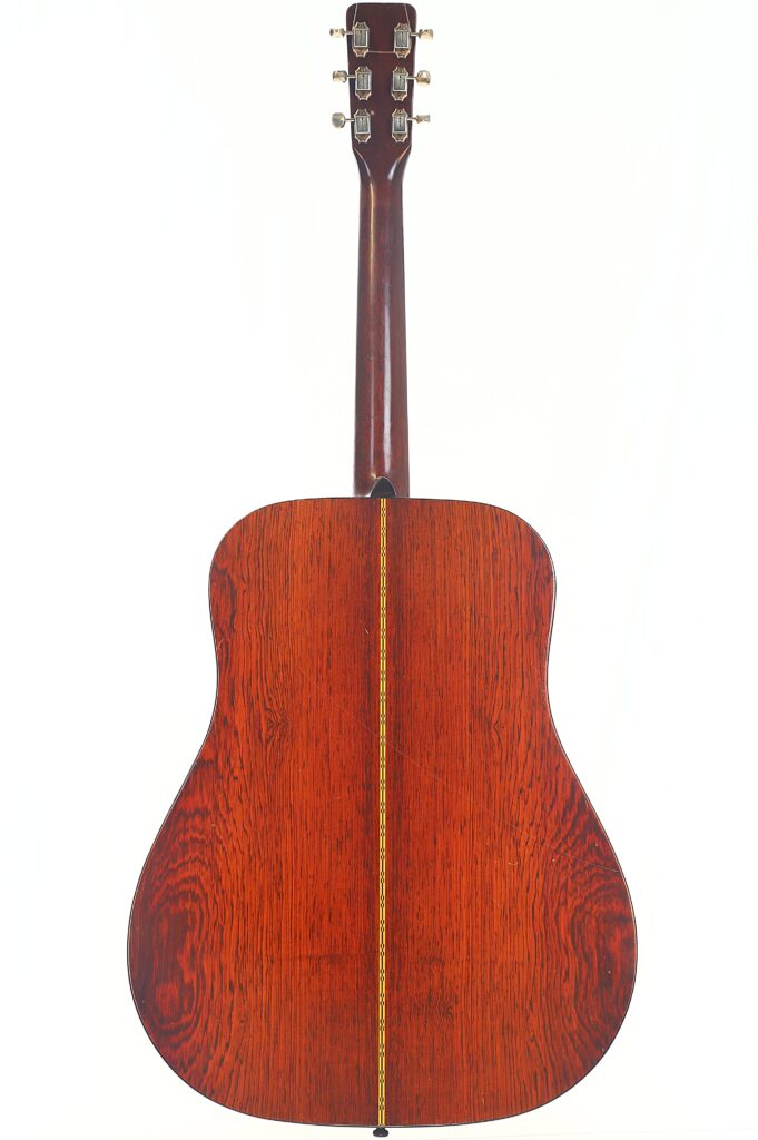 Das Bild zeigt die Rückseite einer Martin D-21 Akustikgitarre aus dem Jahr 1965 mit einem satten, dunklen Holzfinish, sichtbarer Maserung und einer dünnen Ziereinlage in der Mitte. Die Kopfplatte und Stimmwirbel sind ebenfalls zu sehen. Das Bild zeigt die Rückseite einer Martin D-21 Akustikgitarre aus dem Jahr 1965 mit einem satten, dunklen Holzfinish, sichtbarer Maserung und einer dünnen Ziereinlage in der Mitte. Die Kopfplatte und Stimmwirbel sind ebenfalls zu sehen.