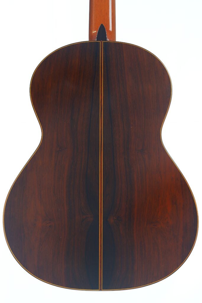 Die Rückseite der „Doble Tapa Klassische Gitarre“ von Manuel Contreras aus dem Jahr 1981 weist eine satte, dunkle Holzmaserung mit einer zentralen Naht und helleren Rändern auf, wodurch die natürlichen Holzmuster und -farben der Gitarre besonders zur Geltung kommen. Die Rückseite der „Doble Tapa Klassische Gitarre“ von Manuel Contreras aus dem Jahr 1981 weist eine satte, dunkle Holzmaserung mit einer zentralen Naht und helleren Rändern auf, wodurch die natürlichen Holzmuster und -farben der Gitarre besonders zur Geltung kommen.