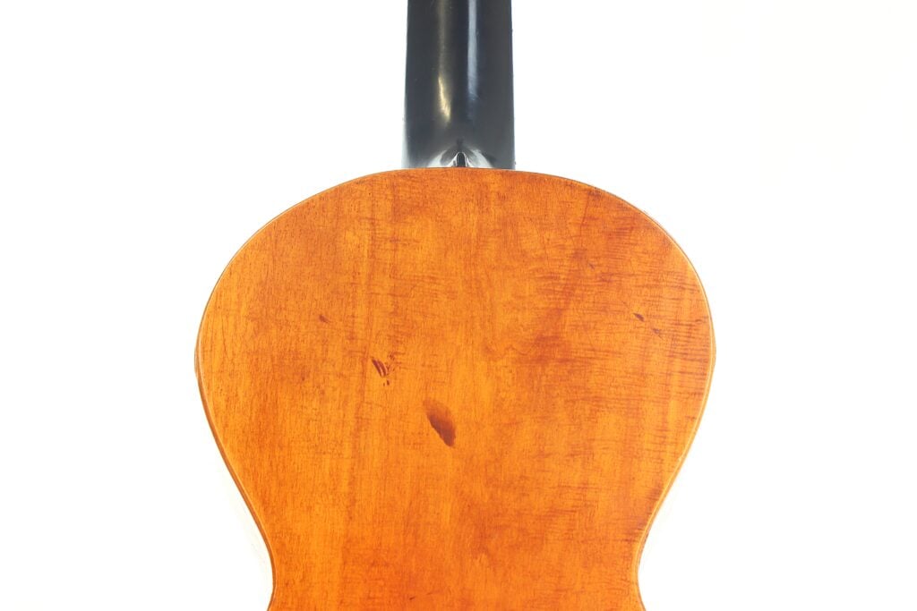Nahaufnahme der Rückseite einer „Romantikgitarre“ von Stephan Thumhart aus dem Jahr 1838 mit einem polierten, hellbraunen Holzkorpus und einem schwarzen Hals vor weißem Hintergrund. Nahaufnahme der Rückseite einer „Romantikgitarre“ von Stephan Thumhart aus dem Jahr 1838 mit einem polierten, hellbraunen Holzkorpus und einem schwarzen Hals vor weißem Hintergrund.