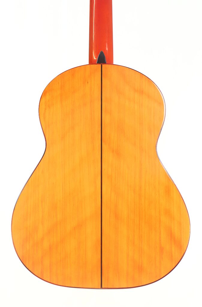 Das Bild zeigt die Rückseite einer José M Palmero 2023 Flamenco-Gitarre mit einer glänzenden, hellorangen Holzoberfläche und einer vertikalen dunklen Mittellinie. Oben ist auch der Hals der Gitarre zu sehen. Das Bild zeigt die Rückseite einer José M Palmero 2023 Flamenco-Gitarre mit einer glänzenden, hellorangen Holzoberfläche und einer vertikalen dunklen Mittellinie. Oben ist auch der Hals der Gitarre zu sehen.