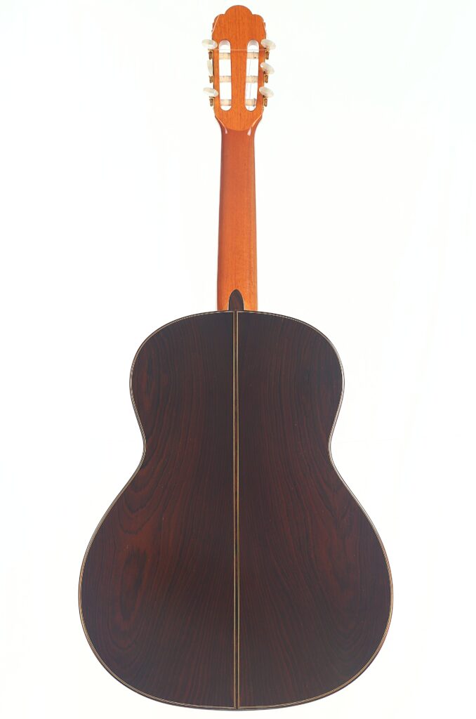Die Vicente Carrillo 1998 Torres Klassische Gitarre ist von hinten abgebildet und zeigt ihren dunklen Holzkorpus mit sichtbarer Maserung und einen helleren braunen Hals, fotografiert vor einem weißen Hintergrund. Die Vicente Carrillo 1998 Torres Klassische Gitarre ist von hinten abgebildet und zeigt ihren dunklen Holzkorpus mit sichtbarer Maserung und einen helleren braunen Hals, fotografiert vor einem weißen Hintergrund.