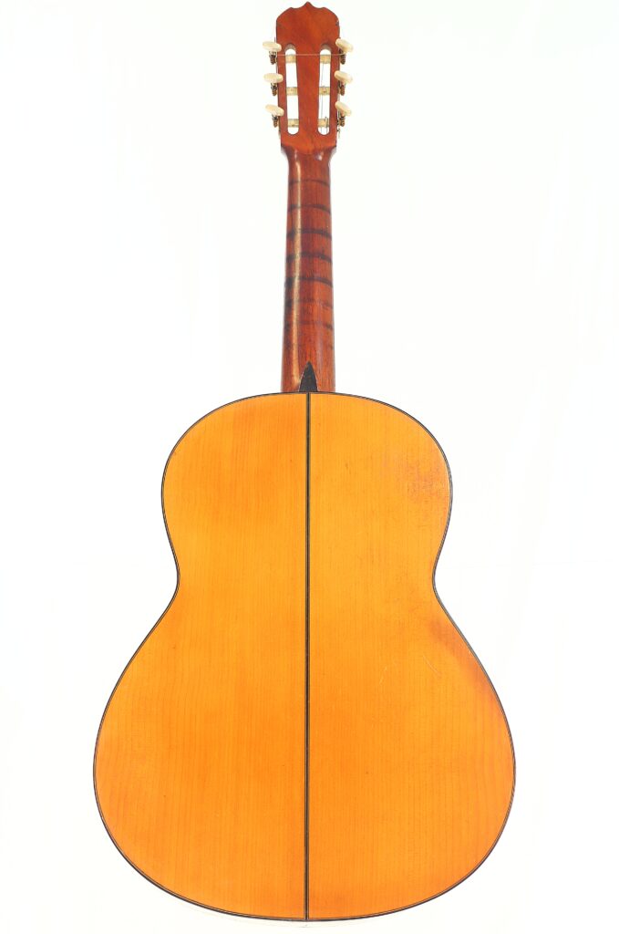 Das Bild zeigt die Rückseite einer Jose Ramirez 1955 Flamenco Gitarre mit einer hellen Holzoberfläche, einer dunklen Mittelnaht und sichtbarer Kopfplatte und Stimmwirbeln an der Oberseite. Das Bild zeigt die Rückseite einer Jose Ramirez 1955 Flamenco Gitarre mit einer hellen Holzoberfläche, einer dunklen Mittelnaht und sichtbarer Kopfplatte und Stimmwirbeln an der Oberseite.
