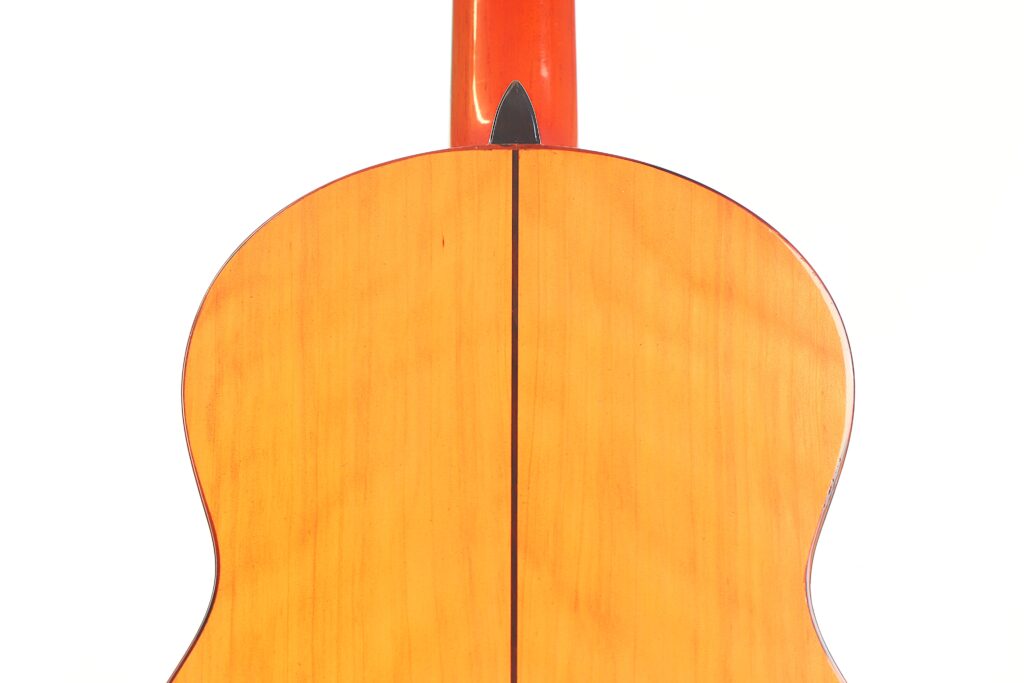 Nahaufnahme des Rückens der José M Palmero 2023 Flamenco-Gitarre, die vor weißem Hintergrund die Maserung des Holzes, die Mittelnaht und die Details des Halses zeigt. Nahaufnahme des Rückens der José M Palmero 2023 Flamenco-Gitarre, die vor weißem Hintergrund die Maserung des Holzes, die Mittelnaht und die Details des Halses zeigt.