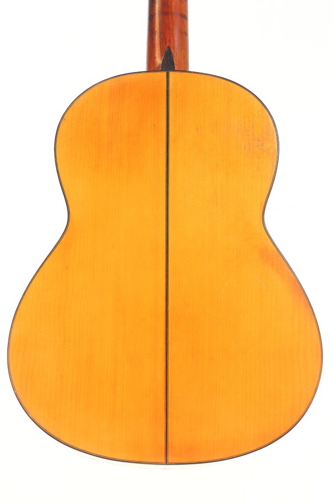Die Rückseite der Jose Ramirez 1955 Flamenco Gitarre hat eine helle Holzoberfläche, eine schlanke schwarze Mittelnaht und anmutig geschwungene Seiten. Die Rückseite der Jose Ramirez 1955 Flamenco Gitarre hat eine helle Holzoberfläche, eine schlanke schwarze Mittelnaht und anmutig geschwungene Seiten.