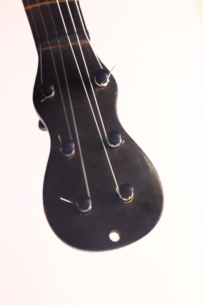 Nahaufnahme des dunklen Kopfes der „Romantikgitarre“ von Stephan Thumhart aus dem Jahr 1838 mit Stimmwirbeln und Metallsaiten vor hellem Hintergrund. Nahaufnahme des dunklen Kopfes der „Romantikgitarre“ von Stephan Thumhart aus dem Jahr 1838 mit Stimmwirbeln und Metallsaiten vor hellem Hintergrund.