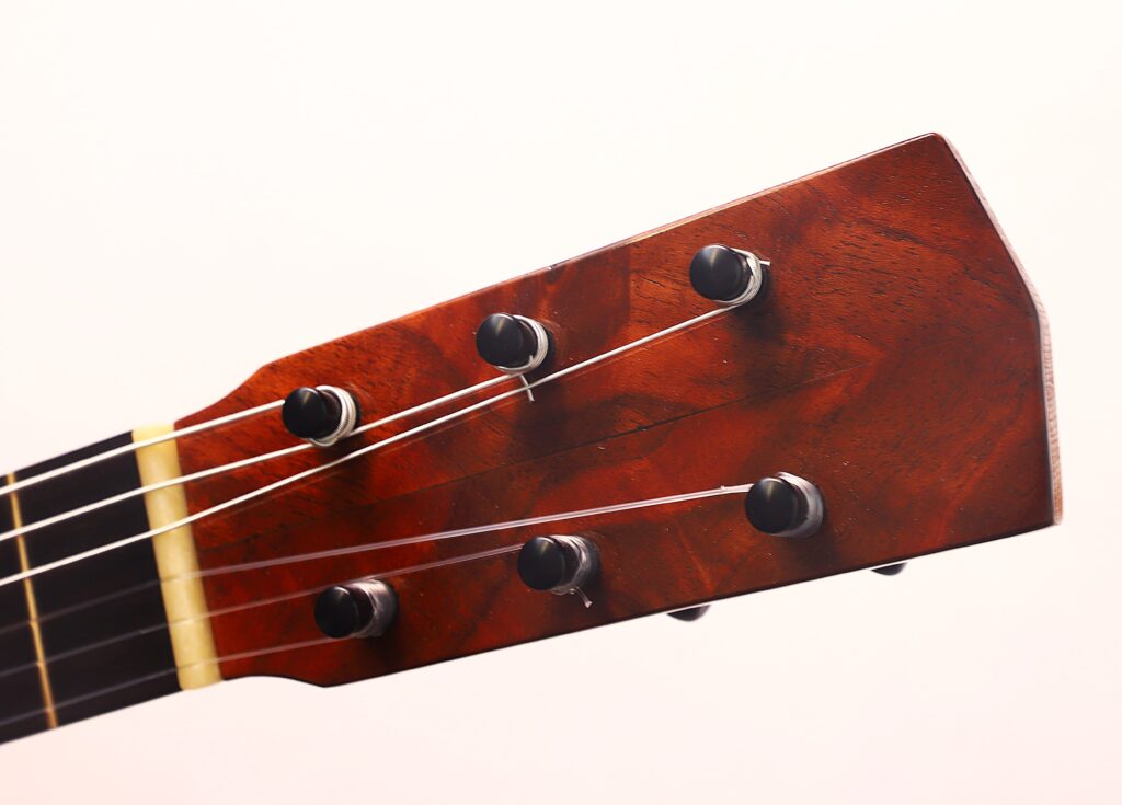 Nahaufnahme der Kopfplatte der Andres Marin 1890 Klassische Gitarre mit sechs Stimmwirbeln und Saiten vor einem schlichten hellen Hintergrund. Nahaufnahme der Kopfplatte der Andres Marin 1890 Klassische Gitarre mit sechs Stimmwirbeln und Saiten vor einem schlichten hellen Hintergrund.