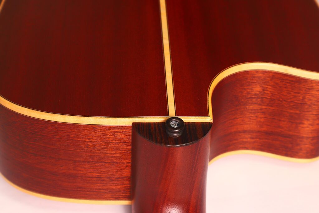 Nahaufnahme der Halsverbindung einer Lakewood D-14-12 Cut 2005 Akustik Gitarre. Hervorzuheben sind die reiche Holzmaserung, die glatte Lackierung und ein Gurtknopf in der Nähe des Halsansatzes. Nahaufnahme der Halsverbindung einer Lakewood D-14-12 Cut 2005 Akustik Gitarre. Hervorzuheben sind die reiche Holzmaserung, die glatte Lackierung und ein Gurtknopf in der Nähe des Halsansatzes.