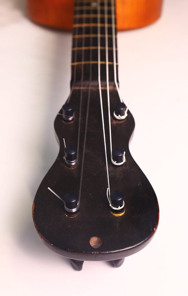 Nahaufnahme des Kopfes einer Romantikgitarre von Stephan Thumhart aus dem Jahr 1838, die die Stimmwirbel und Saiten vor weißem Hintergrund zeigt. Nahaufnahme des Kopfes einer Romantikgitarre von Stephan Thumhart aus dem Jahr 1838, die die Stimmwirbel und Saiten vor weißem Hintergrund zeigt.