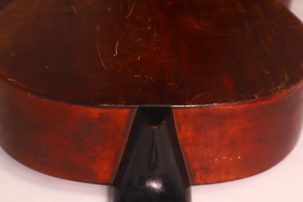 Nahaufnahme des Korpus und des Halsgelenks einer Braun & Hauser 1905 Klassische Gitarre, wobei die polierte, rötlich-braune Holzoberfläche mit sichtbaren Kratzern und Gebrauchsspuren hervorgehoben wird. Nahaufnahme des Korpus und des Halsgelenks einer Braun & Hauser 1905 Klassische Gitarre, wobei die polierte, rötlich-braune Holzoberfläche mit sichtbaren Kratzern und Gebrauchsspuren hervorgehoben wird.