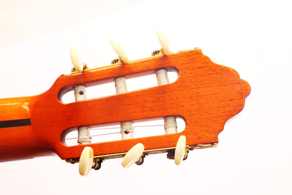 Nahaufnahme der Kopfplatte einer Juan Montero 1993 Blanca Flamenco-Gitarre mit weißen Stimmwirbeln auf weißem Hintergrund. Nahaufnahme der Kopfplatte einer Juan Montero 1993 Blanca Flamenco-Gitarre mit weißen Stimmwirbeln auf weißem Hintergrund.