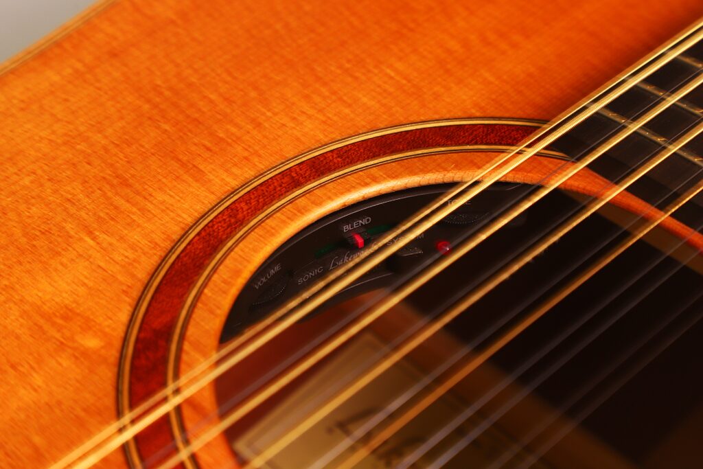Nahaufnahme des Schalllochs der Lakewood D-14-12 Cut 2005 Akustik Gitarre mit Nylonsaiten, einem Teil des internen elektronischen Bedienfelds und einer Holzrosette. Nahaufnahme des Schalllochs der Lakewood D-14-12 Cut 2005 Akustik Gitarre mit Nylonsaiten, einem Teil des internen elektronischen Bedienfelds und einer Holzrosette.
