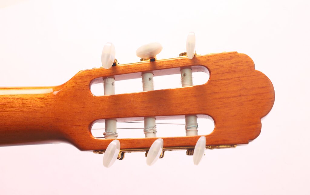 Nahaufnahme der Kopfplatte der Vicente Carrillo 1998 Torres Klassische Gitarre mit sechs weißen Wirbeln und Nylonsaiten vor einem hellen Hintergrund. Nahaufnahme der Kopfplatte der Vicente Carrillo 1998 Torres Klassische Gitarre mit sechs weißen Wirbeln und Nylonsaiten vor einem hellen Hintergrund.