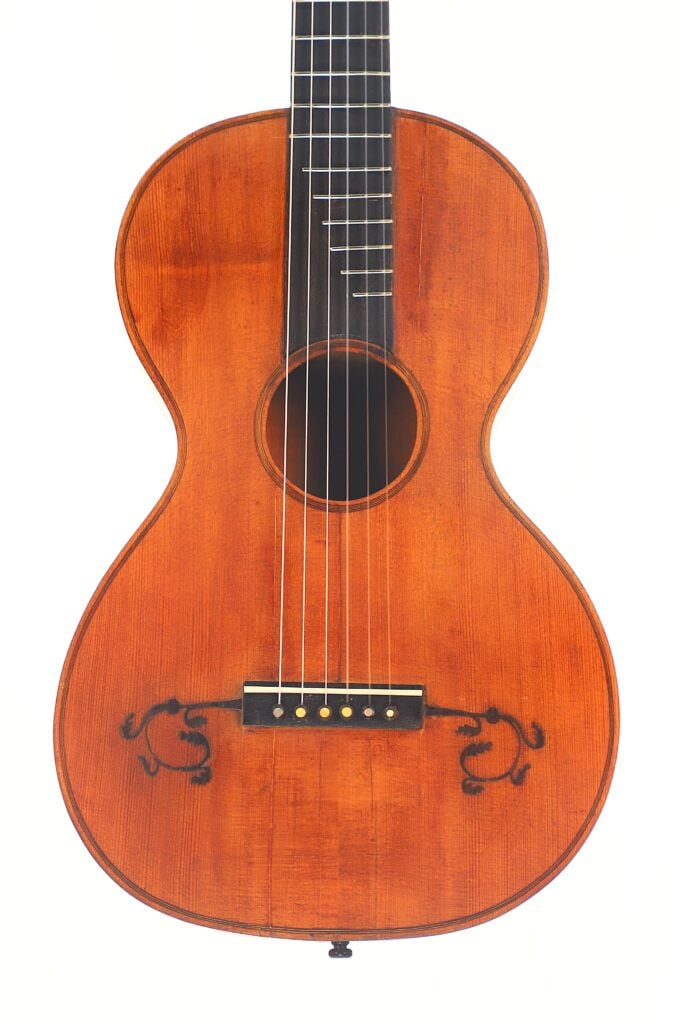 Die „Italienische Romantikgitarre 1860“ ist eine klassische Akustikgitarre mit einem Korpus aus Holz, einem dunklen Griffbrett, sechs Saiten und schwarzen Verzierungen im Bereich des Stegs, die sich vor einem weißen Hintergrund abheben. Die „Italienische Romantikgitarre 1860“ ist eine klassische Akustikgitarre mit einem Korpus aus Holz, einem dunklen Griffbrett, sechs Saiten und schwarzen Verzierungen im Bereich des Stegs, die sich vor einem weißen Hintergrund abheben.