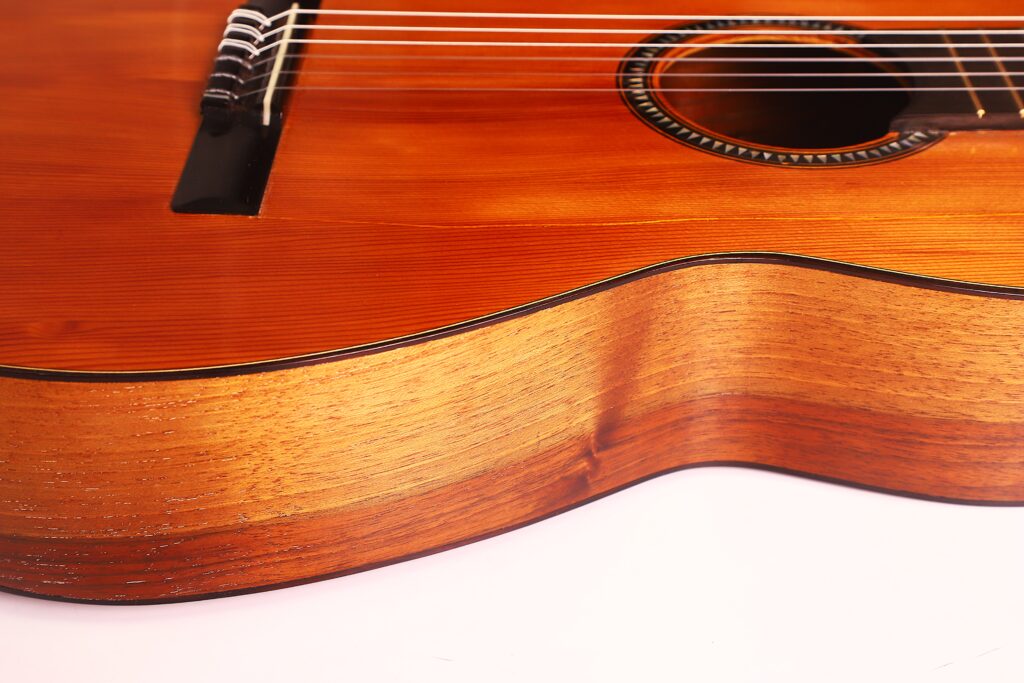 Nahaufnahme des Korpus der Andres Marin 1890 Klassische Gitarre. Hervorzuheben sind die Holzstruktur, die Saiten, das Schallloch und der Steg vor einem weißen Hintergrund. Nahaufnahme des Korpus der Andres Marin 1890 Klassische Gitarre. Hervorzuheben sind die Holzstruktur, die Saiten, das Schallloch und der Steg vor einem weißen Hintergrund.