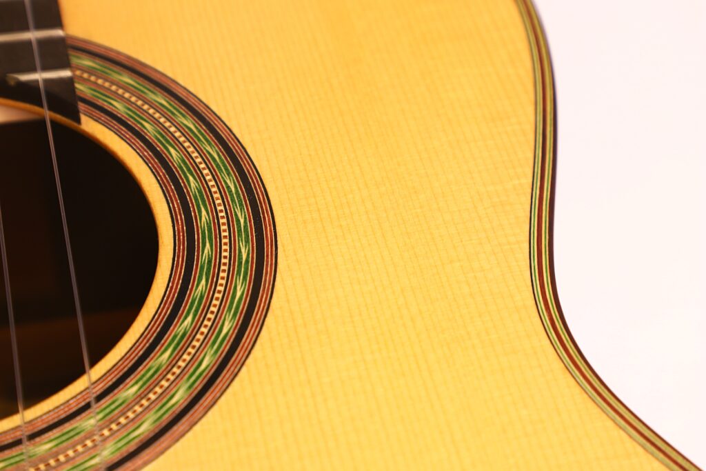 Nahaufnahme der Antonio Aparicio Mod. Master Klassische Gitarre, Hervorhebung des Schalllochs mit dekorativer Einlage, sichtbare Holzmaserung, feine Handwerkskunst und ein Teil der Saiten. Nahaufnahme der Antonio Aparicio Mod. Master Klassische Gitarre, Hervorhebung des Schalllochs mit dekorativer Einlage, sichtbare Holzmaserung, feine Handwerkskunst und ein Teil der Saiten.