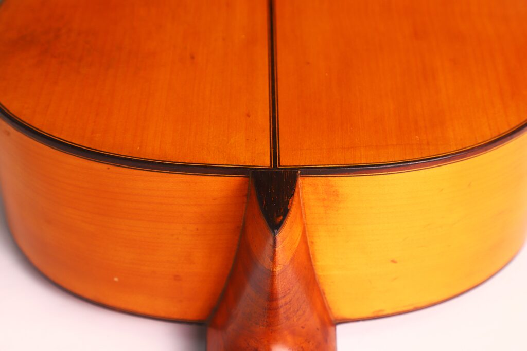 Nahaufnahme der Rückseite einer Flamenco-Gitarre von Jose Ramirez aus dem Jahr 1955, die das Halsgelenk und das glatte, polierte Holz mit sichtbarer Maserung und Nähten zeigt - ein Beweis für außergewöhnliche Handwerkskunst und Details. Nahaufnahme der Rückseite einer Flamenco-Gitarre von Jose Ramirez aus dem Jahr 1955, die das Halsgelenk und das glatte, polierte Holz mit sichtbarer Maserung und Nähten zeigt - ein Beweis für außergewöhnliche Handwerkskunst und Details.