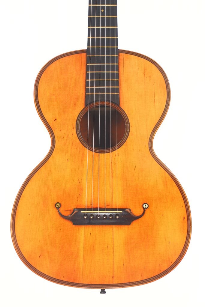 Eine Nahaufnahme der Markneukirchen 1880 Romantikgitarre mit einer natürlichen Holzoberfläche, die die Saiten, das Schallloch, den Steg und das Griffbrett vor einem weißen Hintergrund hervorhebt. Eine Nahaufnahme der Markneukirchen 1880 Romantikgitarre mit einer natürlichen Holzoberfläche, die die Saiten, das Schallloch, den Steg und das Griffbrett vor einem weißen Hintergrund hervorhebt.
