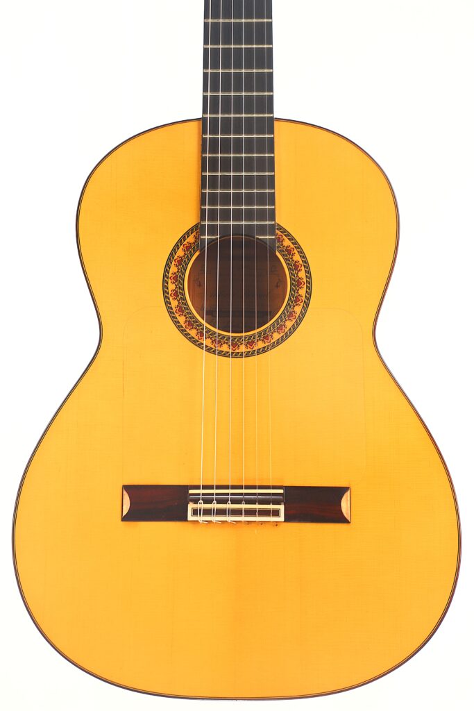 Die Flamenco-Gitarre „Antonio Bernal 2009“ verfügt über einen hellen Holzkorpus, sechs Saiten, eine dekorative Rosette um das Schallloch sowie ein dunkles Griffbrett und wird hier vor weißem Hintergrund abgebildet. Die Flamenco-Gitarre „Antonio Bernal 2009“ verfügt über einen hellen Holzkorpus, sechs Saiten, eine dekorative Rosette um das Schallloch sowie ein dunkles Griffbrett und wird hier vor weißem Hintergrund abgebildet.